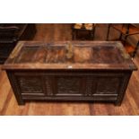 AN 18TH CENTURY OAK COFFER, the hinged four panel top with brass strap hinges above a later carved