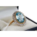 A LADY'S 9CT YELLOW GOLD OVAL BLUE TOPAZ AND DIAMOND SURROUND RING, size P, approximately 5 grams.