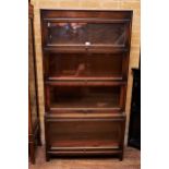 AN EARLY 20TH CENTURY OAK FOUR SECTION GLAZED GUNN BOOKCASE raised on short square legs, 34 ins