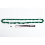A STRING OF GREEN JADE BEADS, 34 ins long and graduated garnet polished BEAD NECKLACE, 16 ins