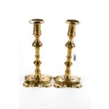 A PAIR OF 18TH CENTURY GEORGE III BRASS CANDLESTICKS with integral facet edge drip pans raised on
