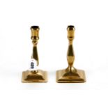 A NEAR PAIR OF 18TH CENTURY BRASS CANDLESTICKS with square baluster stems raised on square bases,