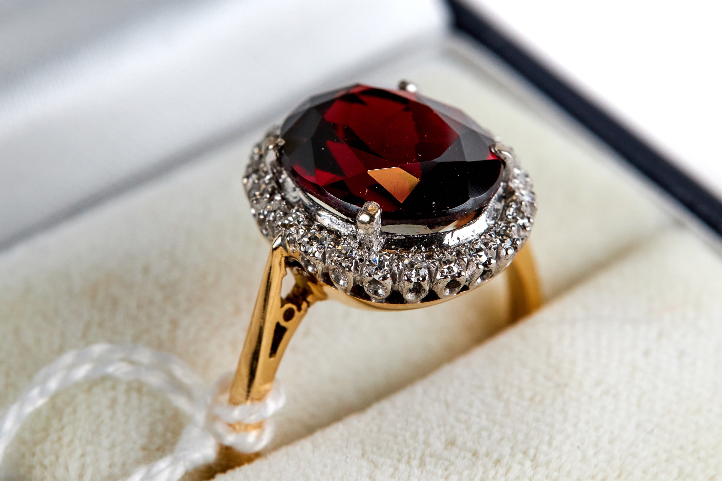 AN 18CT YELLOW GOLD OVAL GARNET AND DIAMOND SURROUND RING, size O, approximately 5.5 grams.