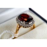 AN 18CT YELLOW GOLD OVAL GARNET AND DIAMOND SURROUND RING, size O, approximately 5.5 grams.