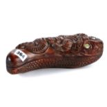 A 20TH CENTURY MAORI CARVED WOODEN FEATHER BOX modelled as a tiki, with shell eyes, 10 ins long.