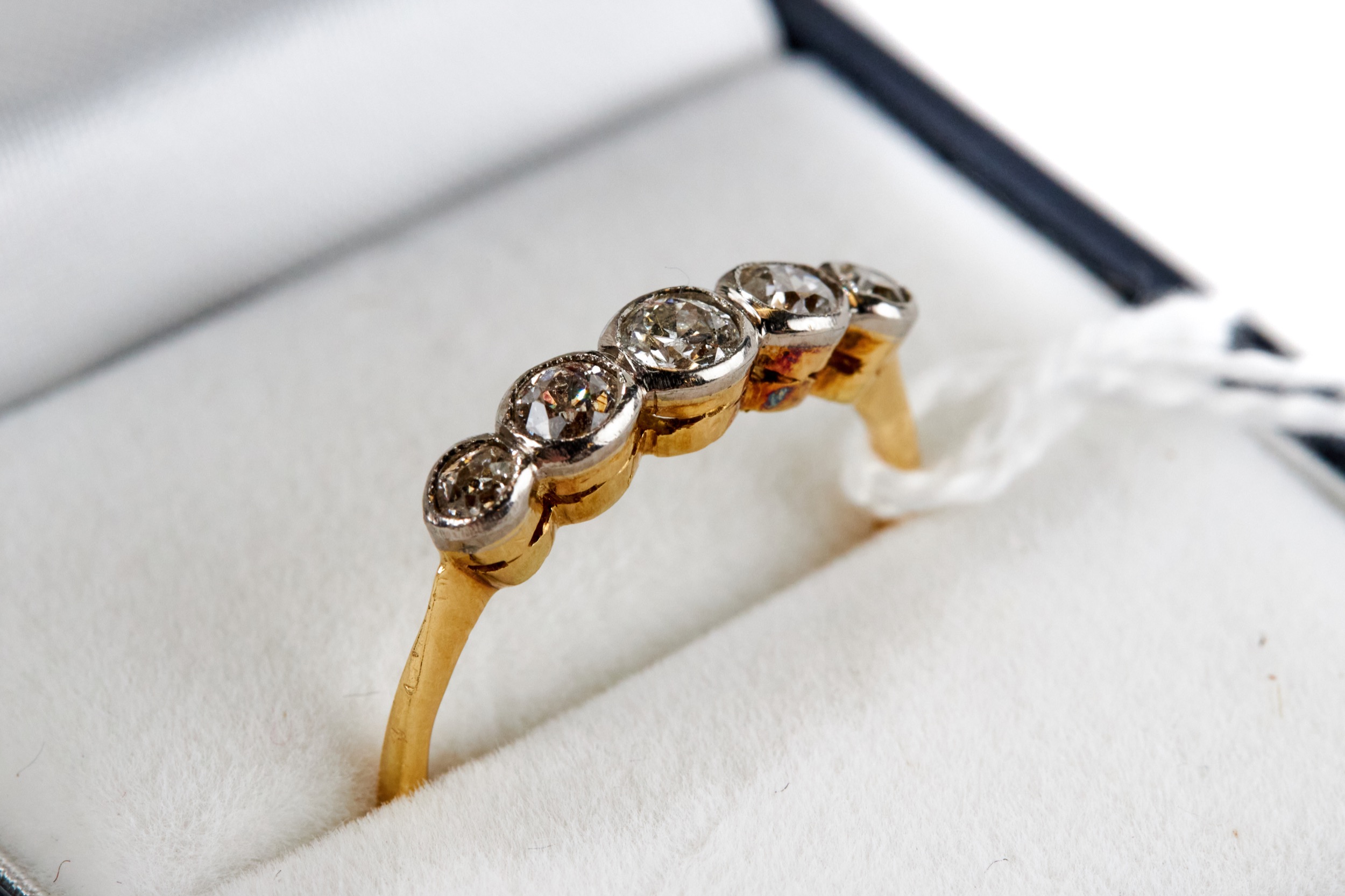 A YELLOW GOLD FIVE STONE COLLET-SET DIAMOND RING, unmarked, size O, approximately 2.3 grams.