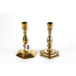 A NEAR PAIR OF 18TH CENTURY BRASS CANDLESTICKS with spool sconces baluster stems on hexagonal
