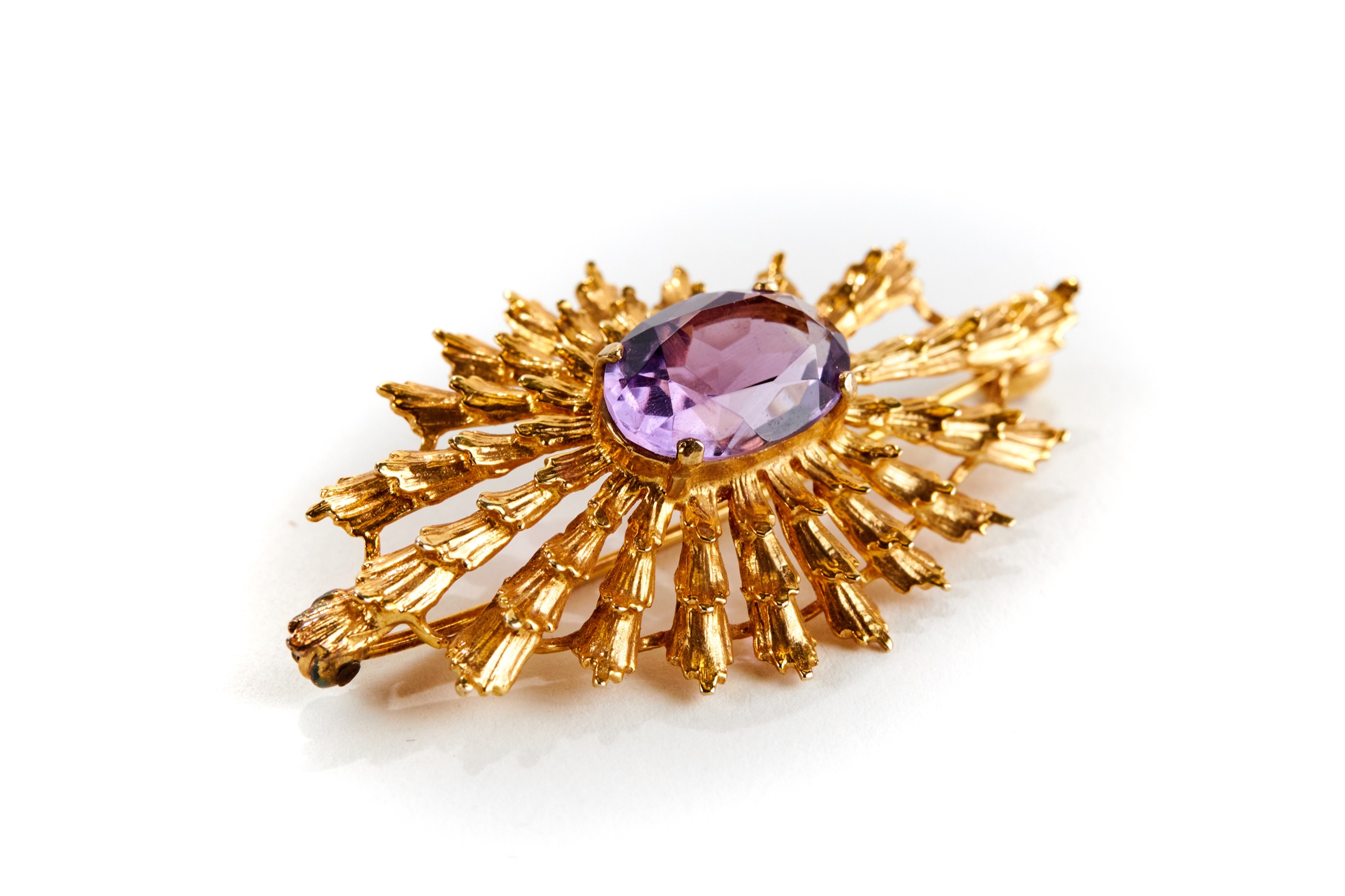 A 9CT YELLOW GOLD SUNBURST STYLE BROOCH set with an amethyst, stamped H.B.J 375, approximately 8.4