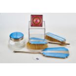 A GEORGE V SILVER AND BLUE GUILLOCHE ENAMEL DRESSING TABLE SET comprising hand mirror, jar and
