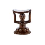 AN AFRICAN CONGO CARVED WOODEN NECK/HEAD REST supported by a squatting female, 8 ins high.