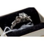 A PERIOD LADY'S 18CT WHITE GOLD SOLITAIRE DIAMOND RING with ribbon-bow shoulders, size M.