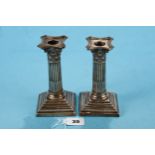 A PAIR OF LATE VICTORIAN CORINTHIAN COLUMN CANDLESTICKS raised on stepped square bases with