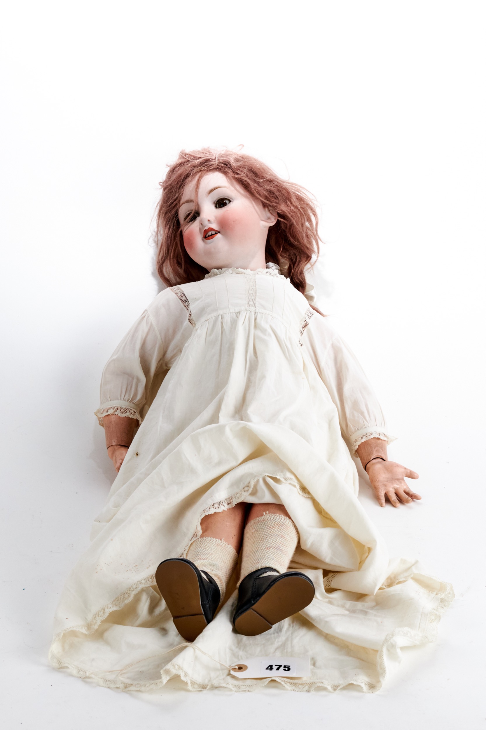 A LATE 19TH/EARLY 20TH CENTURY BISQUE-HEADED DOLL, fixed brown eyes and upper teeth, composition