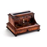 A LATE VICTORIAN WALNUT AND EBONISED CYLINDER FRONT INKSTAND with two internal drawers, twin inkwell
