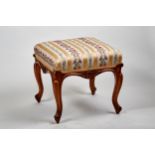 A VICTORIAN WALNUT UPHOLSTERED DRESSING STOOL, shaped foliate carved frieze on cabriole legs, 17 ins