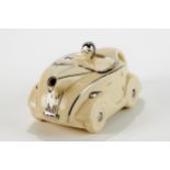 AN ART DECO CREAM GLAZED POTTERY RACING CAR TEAPOT with silvered decoration and registration plate