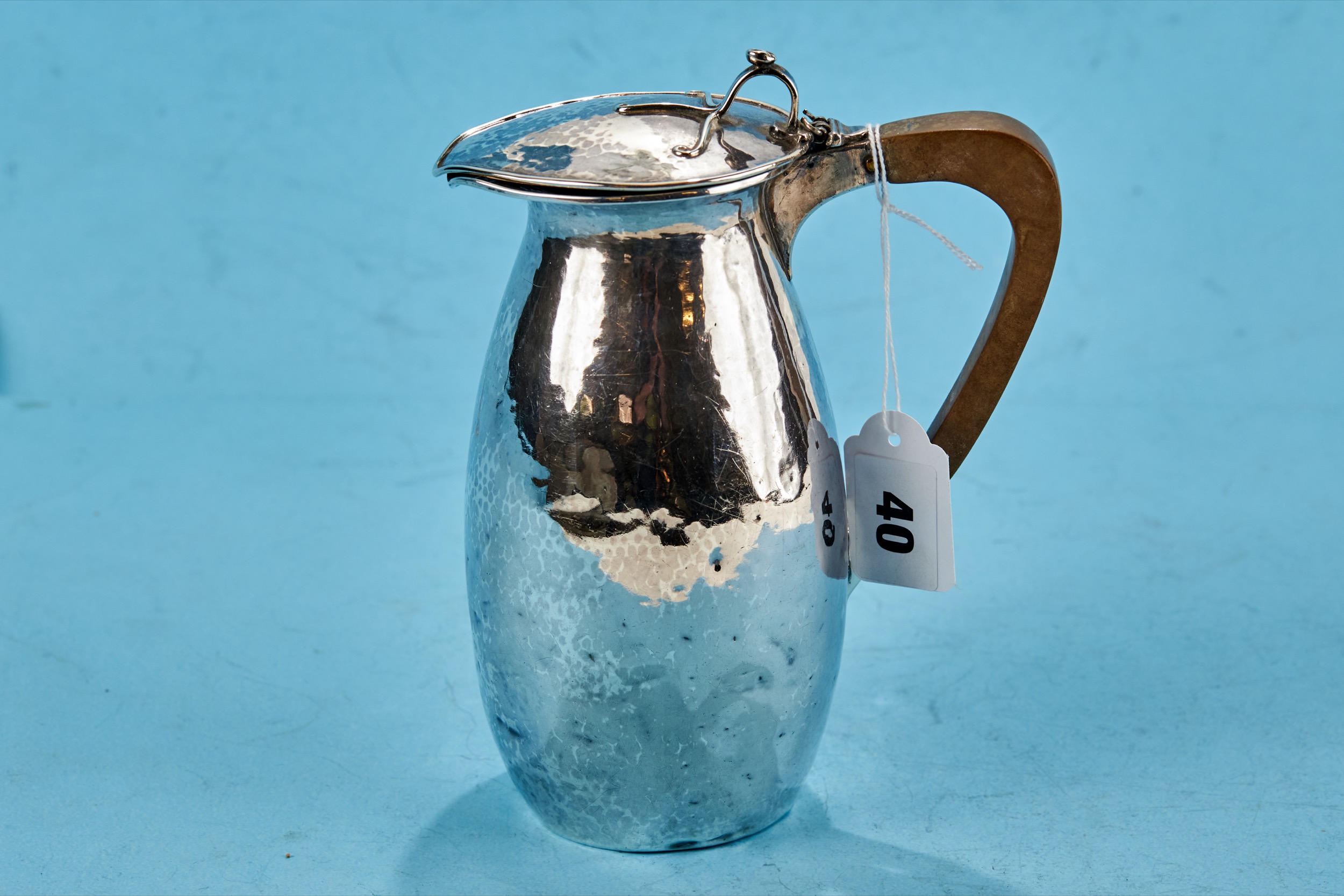 A GEORGE V SILVER ARTS AND CRAFTS INFLUENCE HOT WATER JUG, spot hammered with tendril thumb piece,