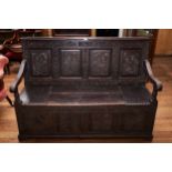 A 19TH CENTURY OAK BOX SEAT SETTLE, the carved four panel back with pseudo 1698 date, hinged seat,