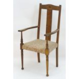 An early 20thC Arts & Crafts style open armchair with shaped top rail above a central rectangular