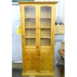 A pine glazed bookshelf with cupboard under Please Note - we do not make reference to the