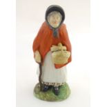 An 18th / 19thC Staffordshire figure modelled as an old lady in a bonnet carrying basket. Approx. 7"