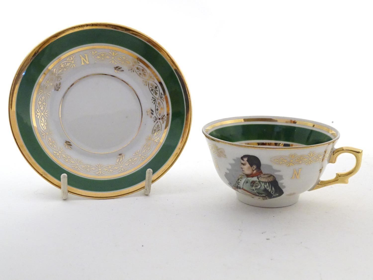 A French tea cup and saucer depicting Emperor Napoleon with green and gilt highlights. Porcelaine de