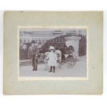 A Victorian monochrome photograph, depicting two children leading a goat pulling a small