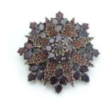 A Victorian gilt metal brooch of star form, set with a profusion of garnets. Approx 1 1/2" wide