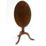An early 19thC mahogany tripod table, having an oval shaped top above a turned stem and three
