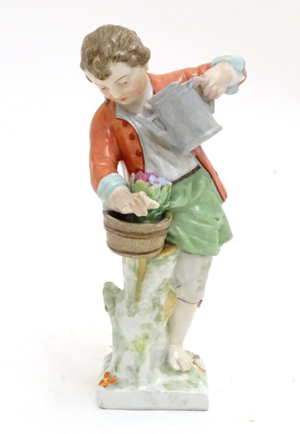 A Continental porcelain figure modelled as a boy with a watering can tending to a pot of flowers.