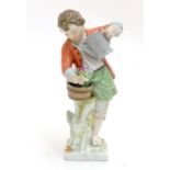 A Continental porcelain figure modelled as a boy with a watering can tending to a pot of flowers.