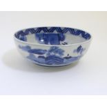 A Chinese blue and white bowl with hand painted decoration depicting an Oriental landscape with