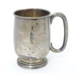 A silver mug with loop handle and engraved woodpecker on branch . Possibly and an early logo for