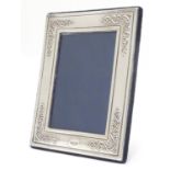 A photograph frame with silver surround having scrollwork decoration at each corner. Hallmarked