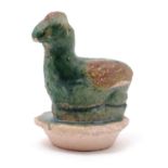 An Oriental clay zoomorphic jar stopper of stylised chicken form with a green and red glaze. Approx.