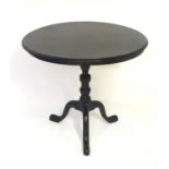A 19thC ebonised tripod table with a circular top above a turned tapering stem and three cabriole