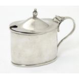 A silver mustard pot of oval form with loop handle and blue glass liner, hallmarked Birmingham