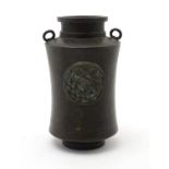 A Oriental bronze vase with twin loop handles and relief roundel decoration depicting a vine leaf