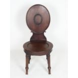 A Regency mahogany hall chair with a rounded back, moulded centre and a scrolled shaped support.