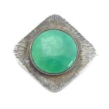 An Arts & Crafts brooch set with green Ruskin style cabochon within a textured silver mount,