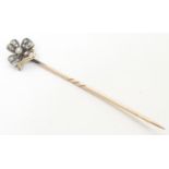 A gold stick pin surmounted by flower / shamrock / clover set with diamonds and seed pearl to