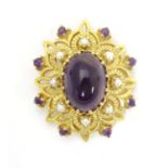 A 9ct gold brooch set with central oval cabochon amethyst surrounded by eight seed pearls, further