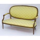 An early 20thC sofa with a carved giltwood frame and upholstered back rest and seat above four