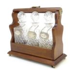 A 20thC tantalus with three cut glass decanters. Approx. 12" high Please Note - we do not make