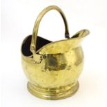 A late 19th / early 20thC brass coal scuttle of helmet form with a swing handle and small rear