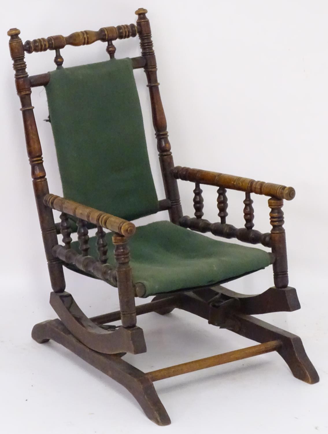 An early 20thC childs rocking chair with a ring turned frame above a cloth seat and turned spindle