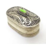 A silver plate pill box of ovoid form with filigree style detail to lid and green stone cabochon.