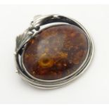 A silver brooch set with amber cabochon to centre. Approx 1 3/4" wide Please Note - we do not make