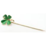 A gold stick pin surmounted by a shamrock / four leaf clover with green guilloche enamel