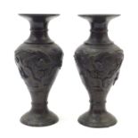 A pair of Japanese cast metal vases decorated with birds amongst trees and foliage in relief.